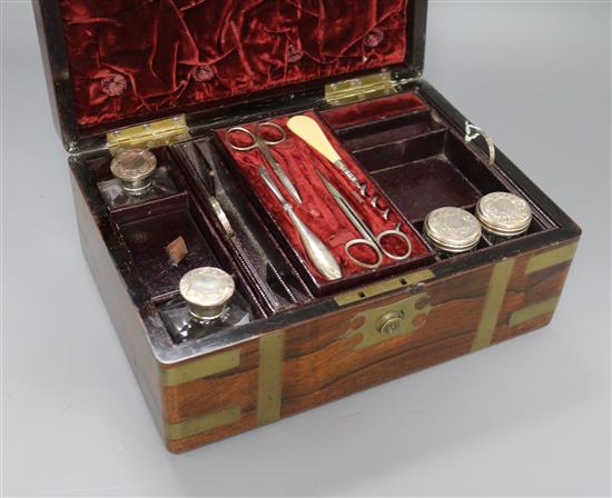 A Victorian brass mounted rosewood toilet box, containing four silver mounted bottles and four nail implements, box 28cm.